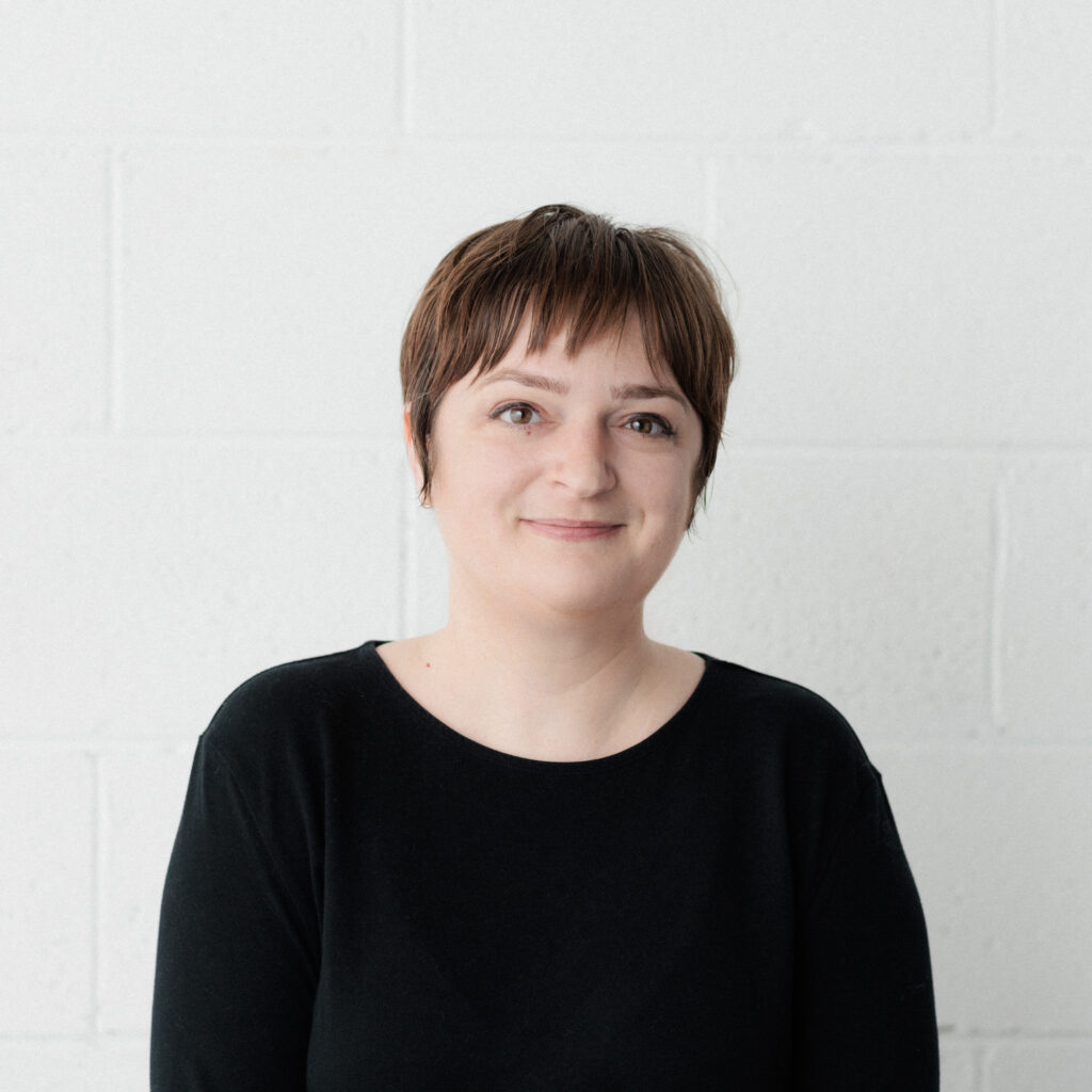 A headshot of Meg. They have short hair and are wearing a black shirt.